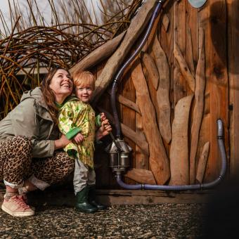 Mother crouching down with young child smiling in outdoor playground
